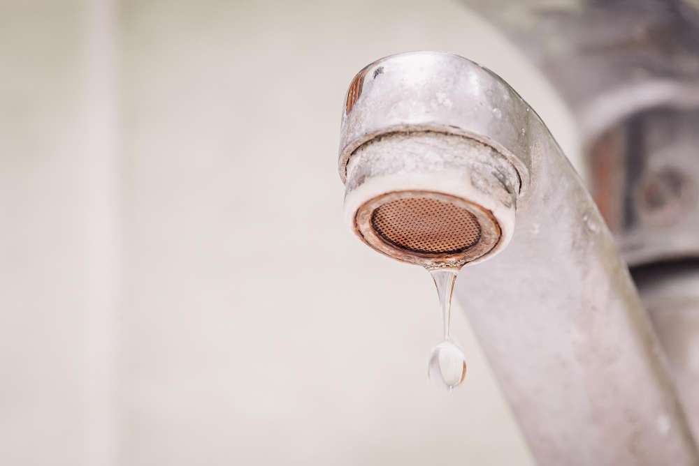 Close-up of faucet with mineral buildup from hard water and slow drip